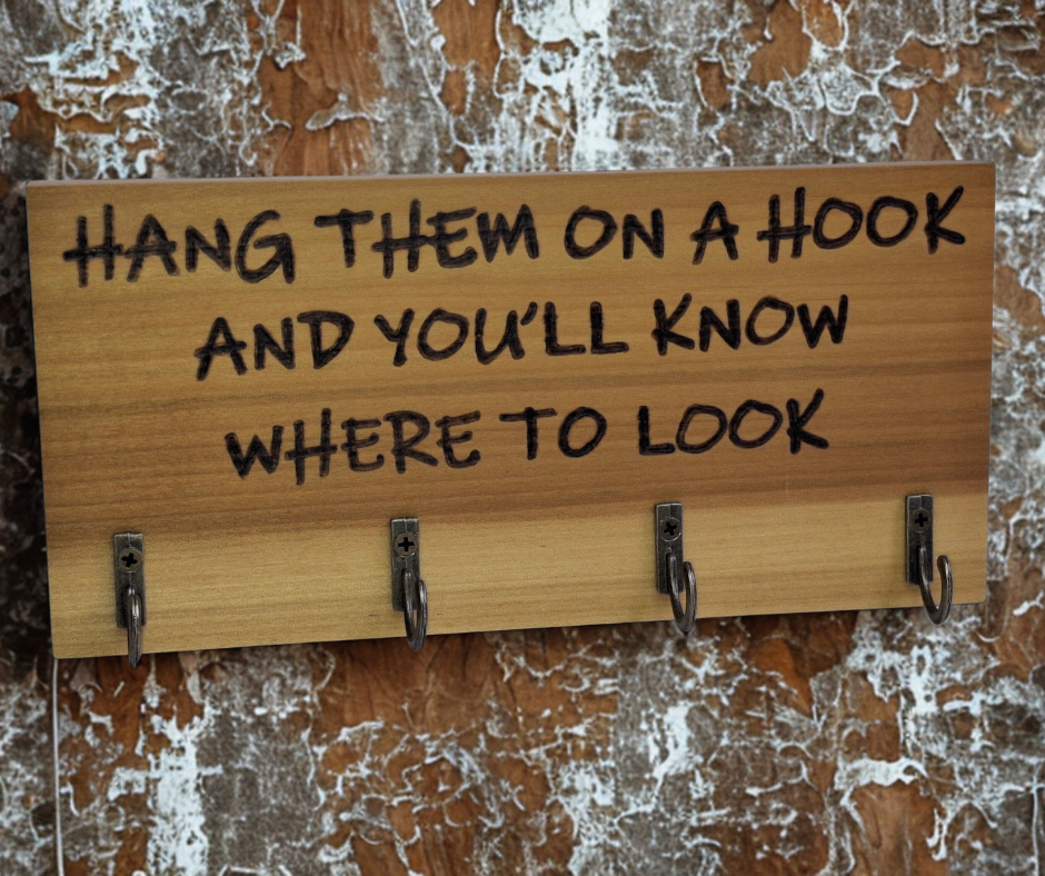 A four-key hook hanger crafted from two-tone Tulipwood, featuring hand-burnt lettering that reads "Hang them on a hook so you know where to look." The wood has visible grain, showcasing its natural variations.