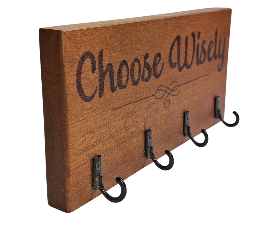 A dark sapele wood 4-hook key hanger with hand-decorated pyrography wording "Choose Wisely" and a small decorative line in the center.