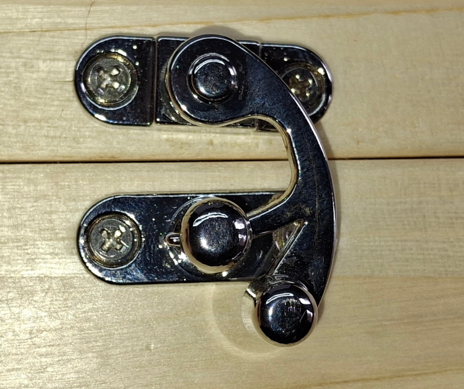 Polished chrome toggle catch for secure closure, located in the center of the box front