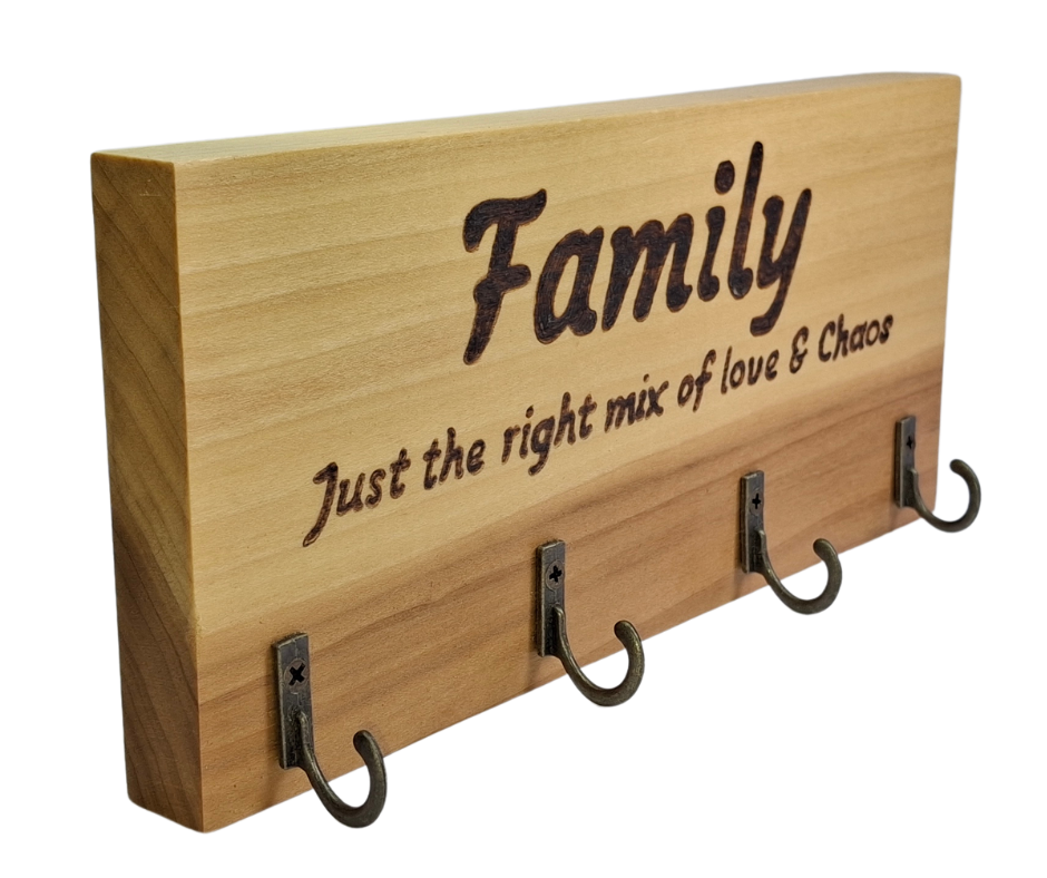 A four-key hook hanger crafted from two-tone Tulipwood, featuring hand-burnt lettering that reads "Family just the mix of love & chaos." The wood has visible grain, showcasing its natural variations.