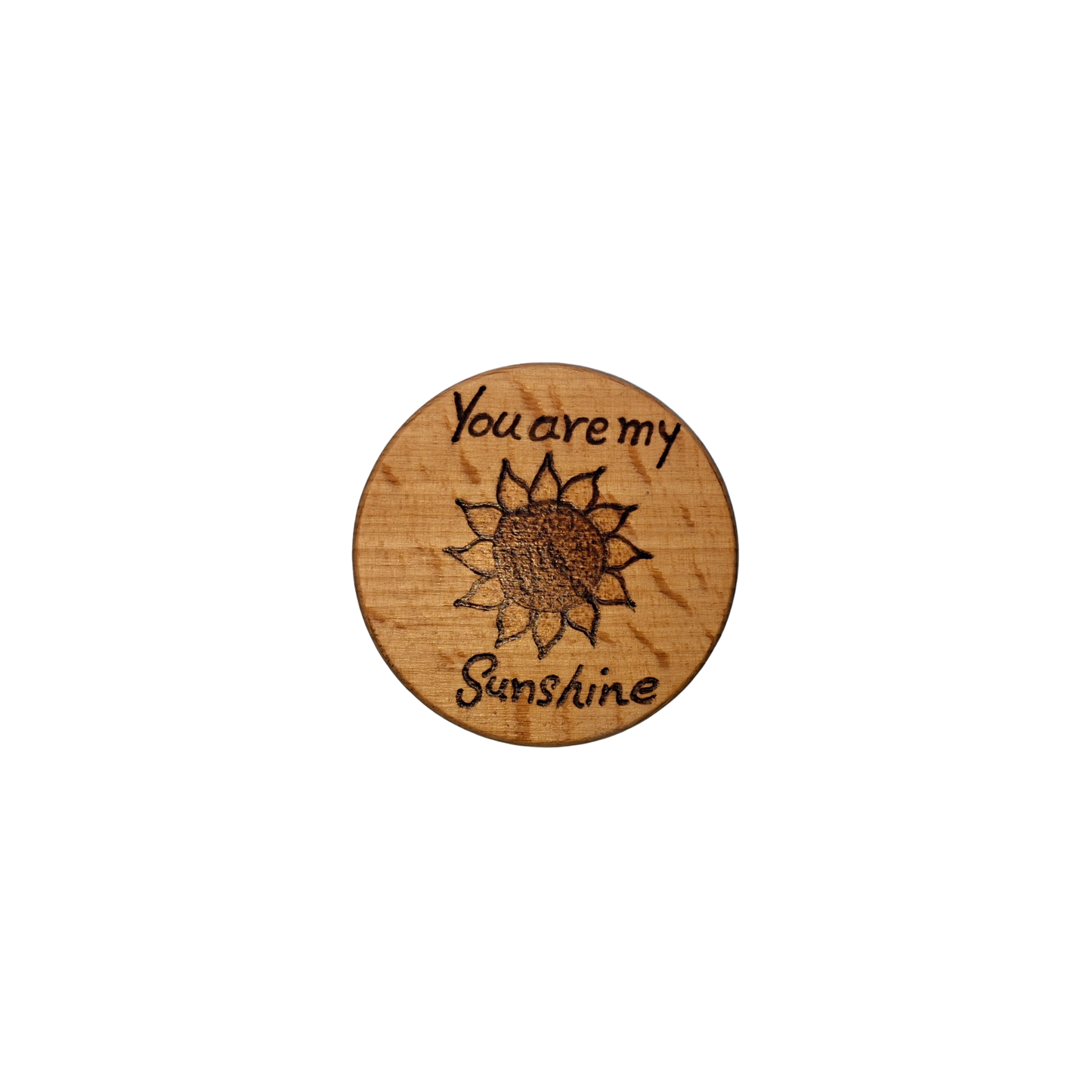 Close-up of a light-colored beechwood circle, 5cm in diameter and 0.4cm thick, featuring the words "You are my sunshine" and an illustration of a sunflower hand-burned into its surface using pyrography. The wood has a smooth, waxed finish and the text is clearly legible.