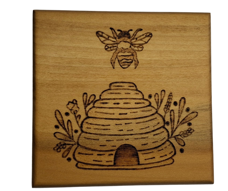 Tulipwood coaster with chamfered edges with a bee flying over a hive design burnt in