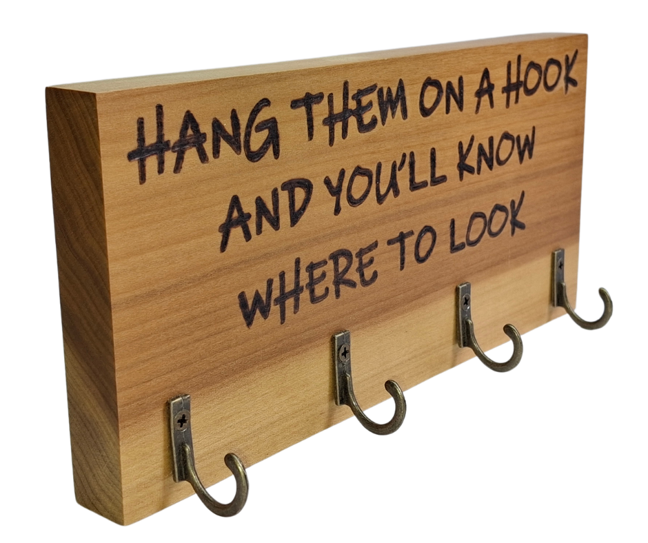 A four-key hook hanger crafted from two-tone Tulipwood, featuring hand-burnt lettering that reads "Hang them on a hook so you know where to look." The wood has visible grain, showcasing its natural variations.