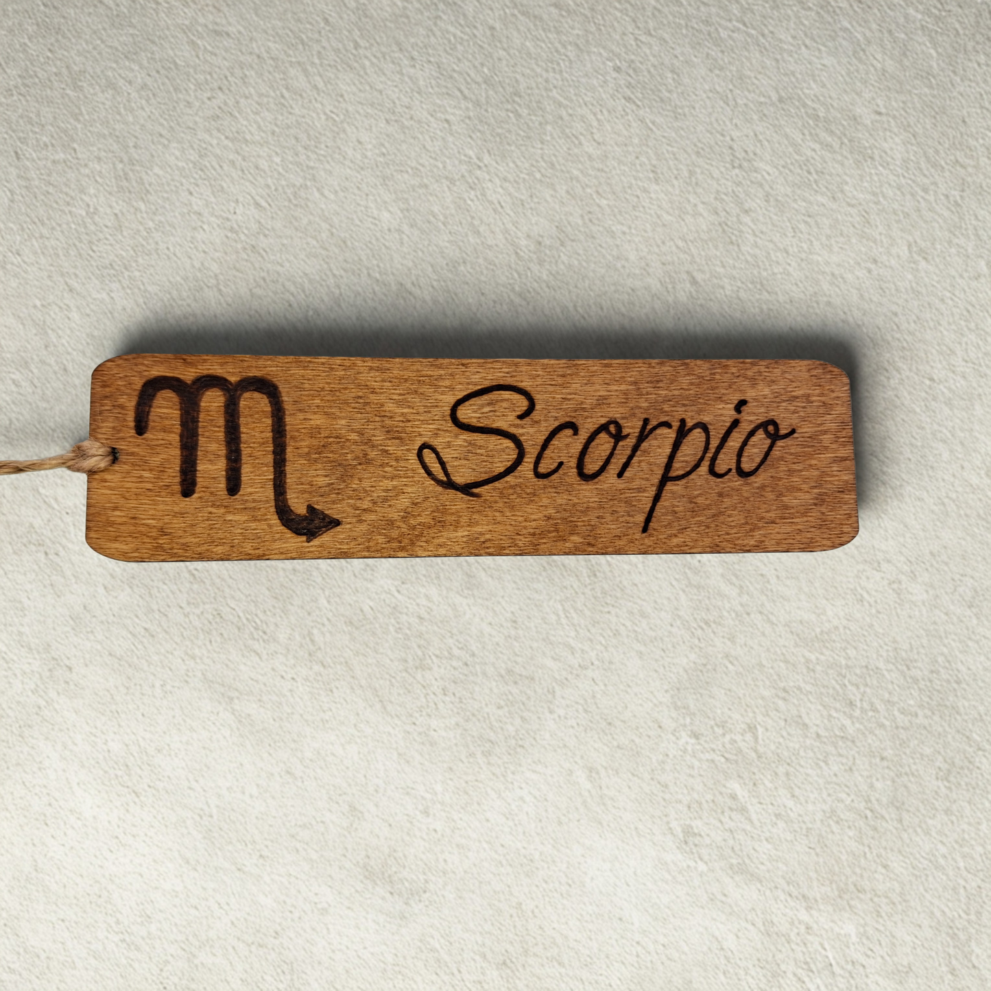 Dark wood bookmark with "Scorpio" pyrography and a star sign illustration.