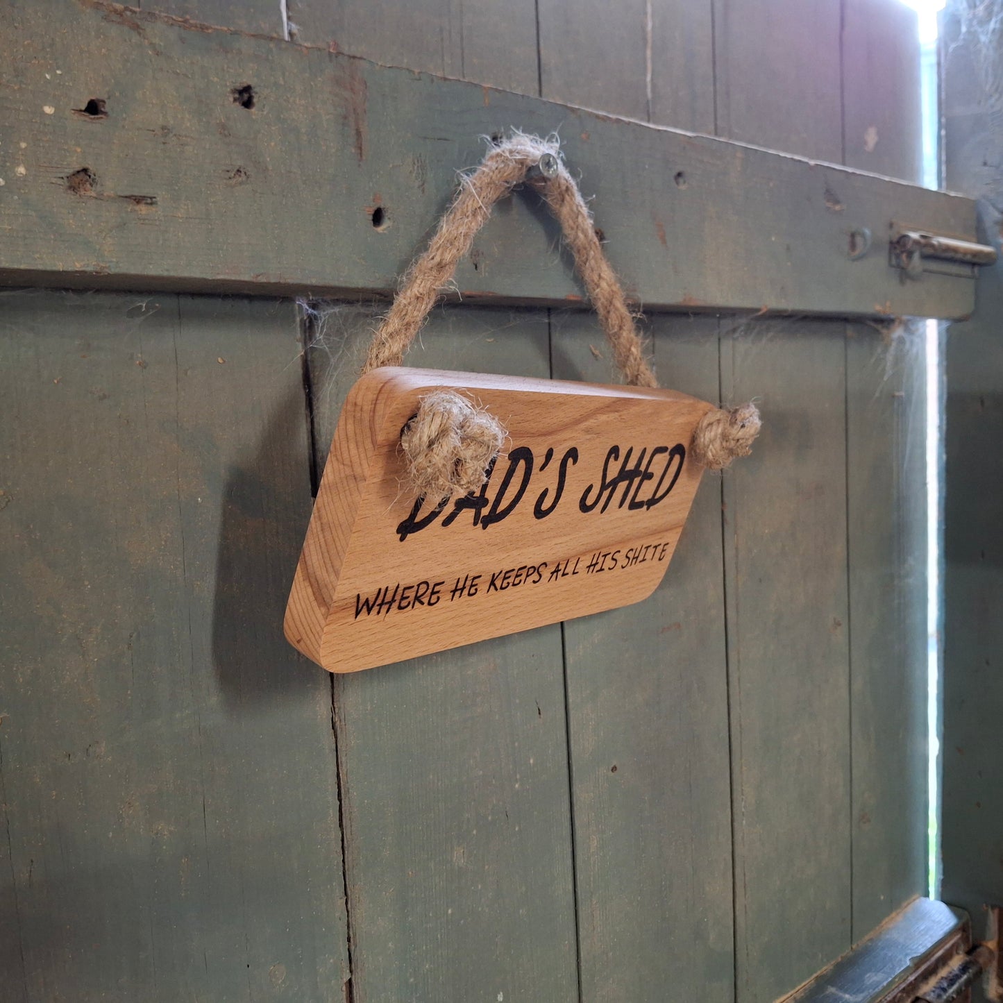 Wooden sign with 'Dad's Shed' text hanging on a wooden door.