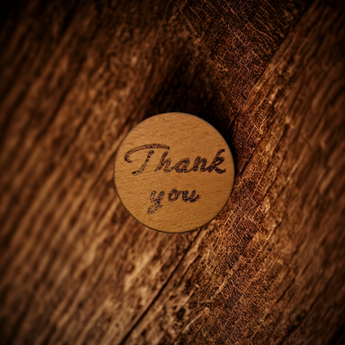 Close-up of a light-colored beechwood circle, 5cm in diameter and 0.4cm thick, featuring the words "Thank You" hand-burned into its surface using pyrography. The wood has a smooth, waxed finish and the text is clearly legible.