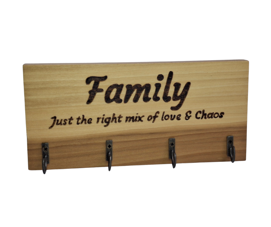 A four-key hook hanger crafted from two-tone Tulipwood, featuring hand-burnt lettering that reads "Family just the mix of love & chaos." The wood has visible grain, showcasing its natural variations.