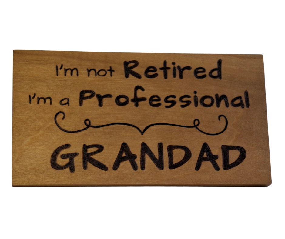 Hand-burnt wooden sign featuring the witty "I'm not retired I'm a professional Grandad" text, separated by a charming pyrography divider.