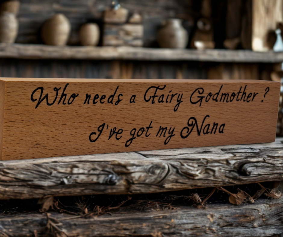A hand-burnt, freestanding wooden plaque with the words "Who needs a fairy godmother I've got my Nana" in a casual, handwritten style. The wood has visible grain and a rustic, natural finish.