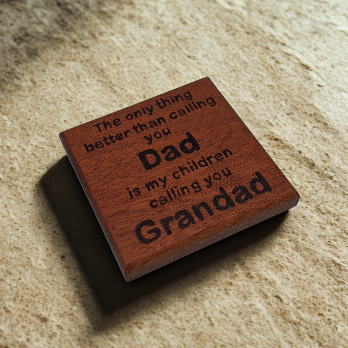 Dark wooden coaster with pyrography text reading 'The only thing better than calling you Dad is my children calling you Grandad'