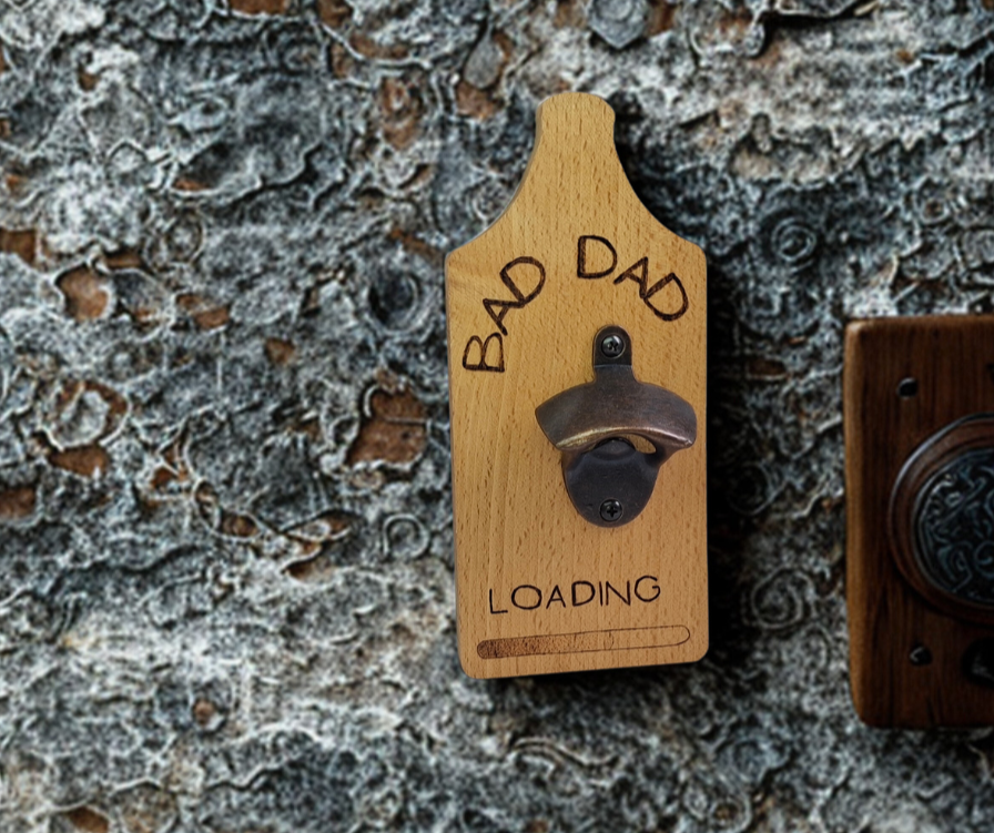 Decorative wall-mounted Beechwood bottle opener with a rustic metal opener, intricately hand-decorated with "Bad Dad... Loading" text