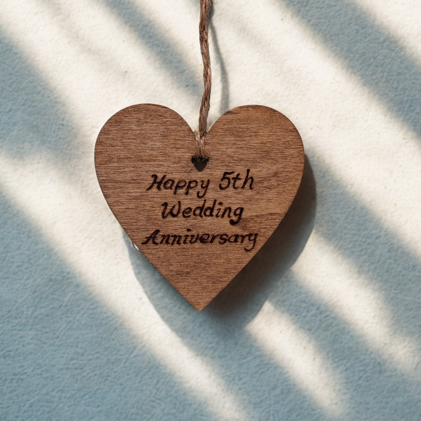 Wooden heart-shaped ornament with 'Happy 5th Wedding Anniversary' engraved text and natural jute string for han.ging