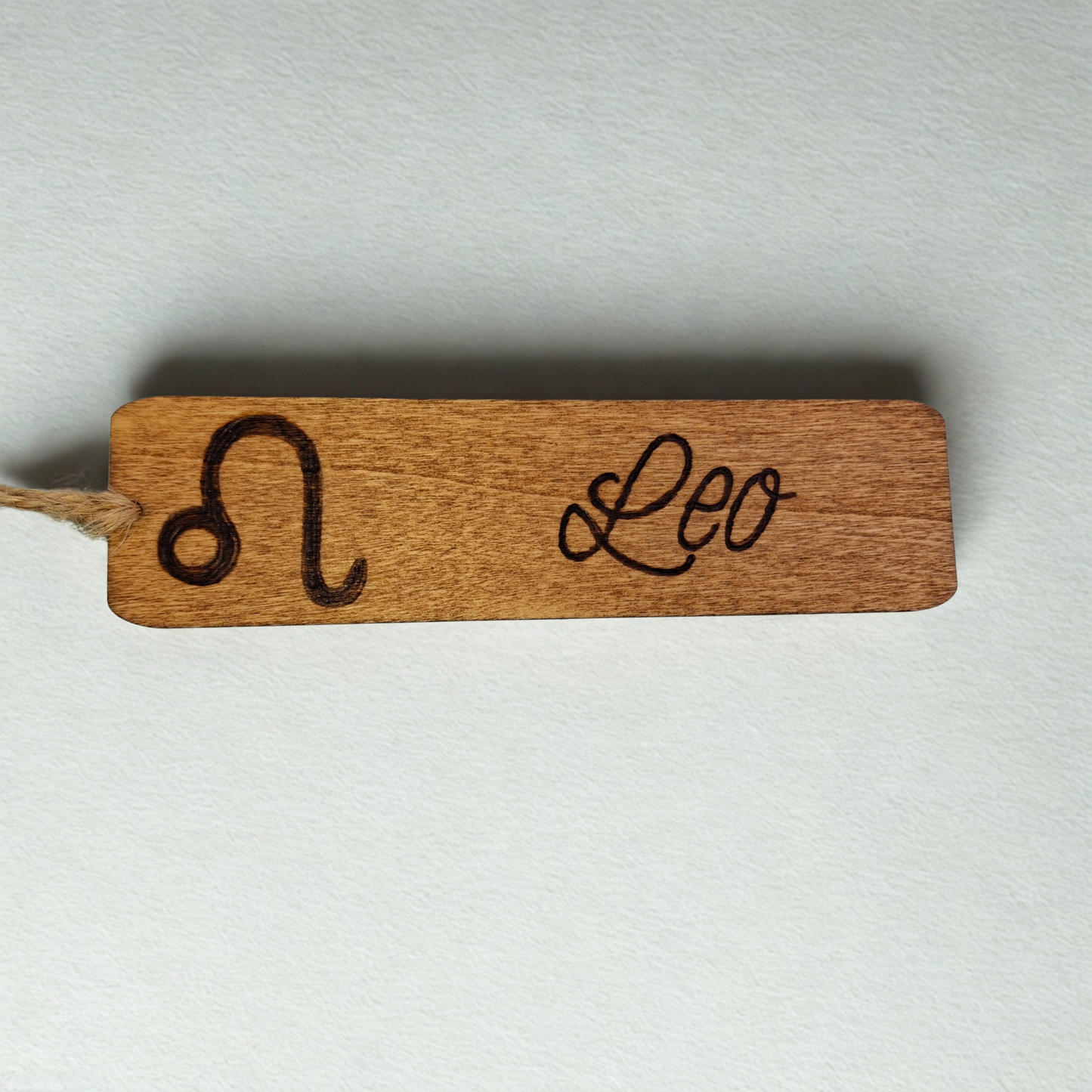 Dark wood bookmark with "Leo" pyrography and a star sign illustration.