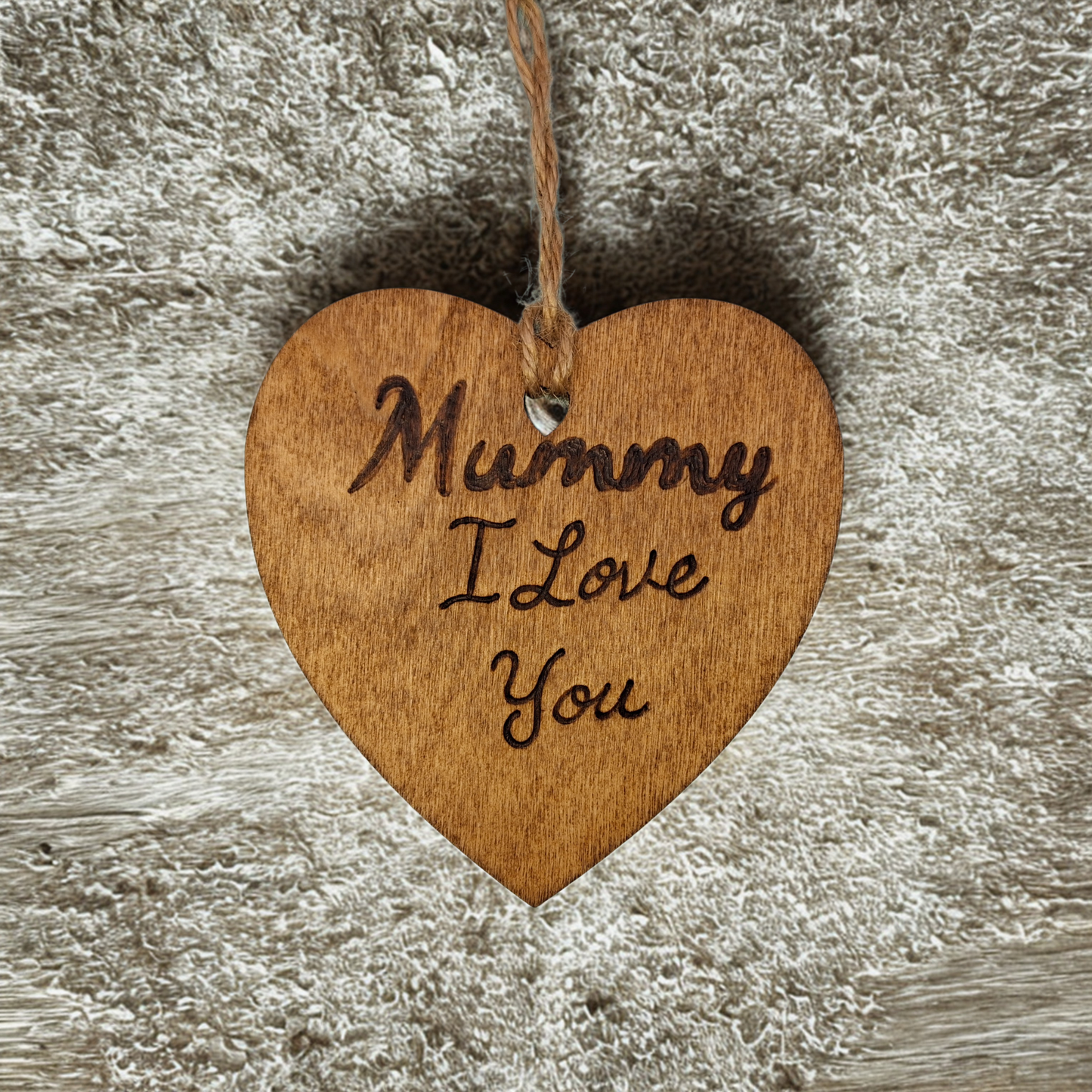 Heart-shaped wooden ornament, hand-drawn with pyrography, featuring the engraved phrase "Mummy I Love you" in a decorative script, set against a textured background.