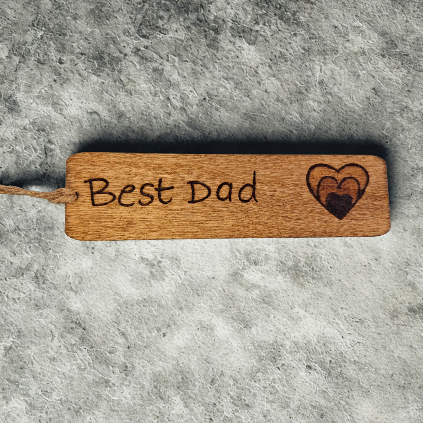 Dark wood bookmark with "Best Dad" pyrography and a heart illustration.