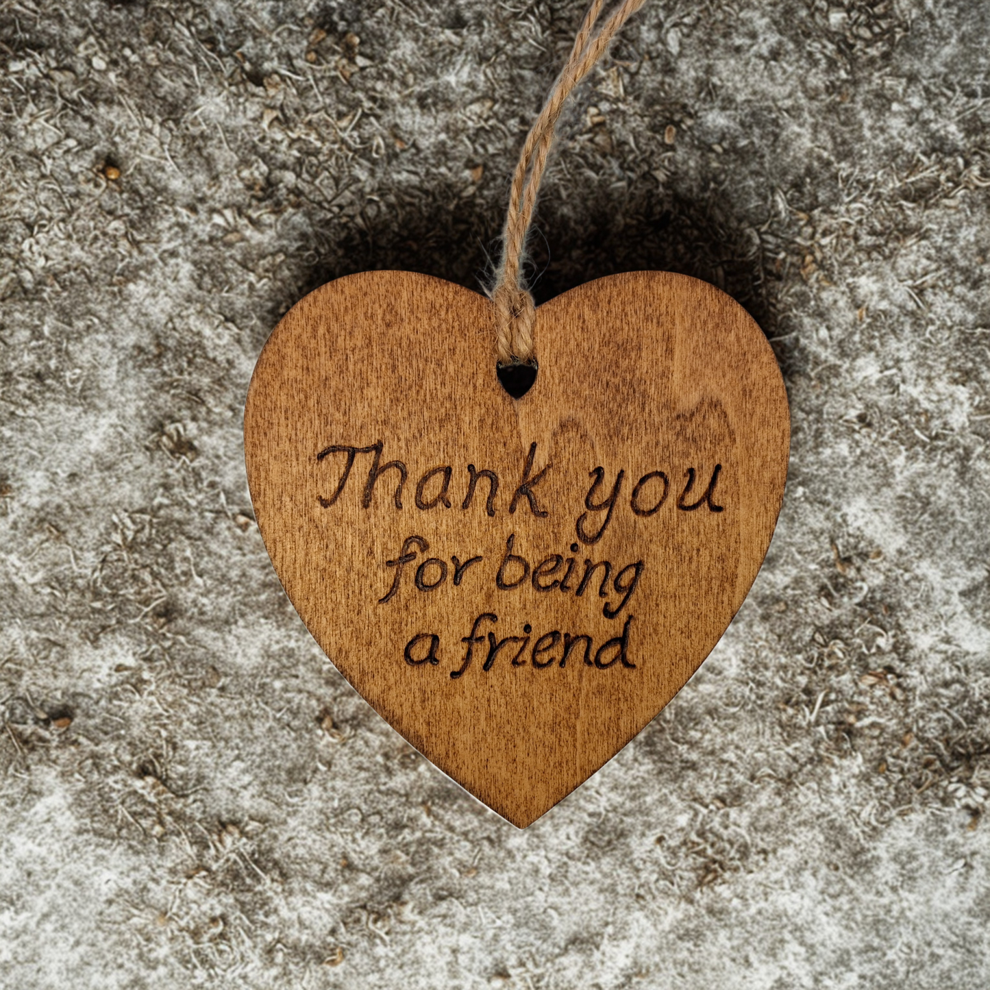Heart-shaped wooden ornament, hand-drawn with pyrography, featuring the engraved phrase "Thank you for being a friend" in a decorative script, set against a light, plain background.