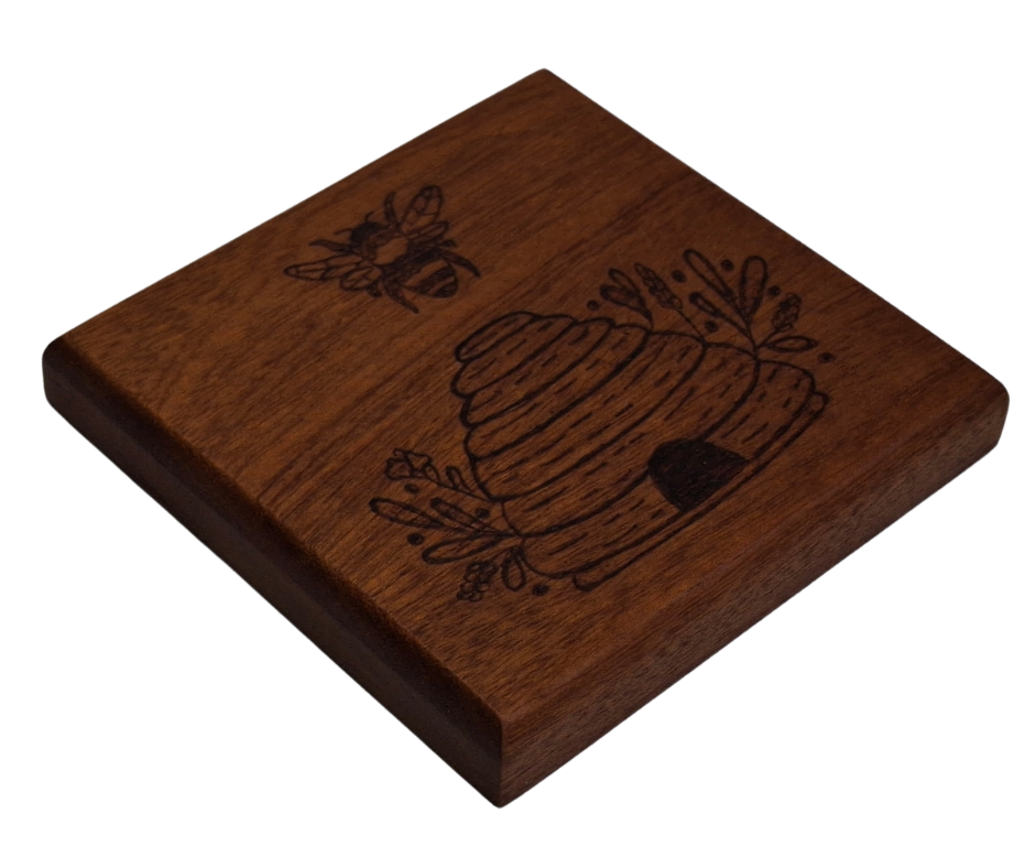 Sapele coaster with chamfered edges with a bee flying over a hive design burnt in