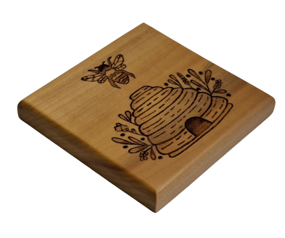 Tulipwood coaster with chamfered edges with a bee flying over a hive design burnt in