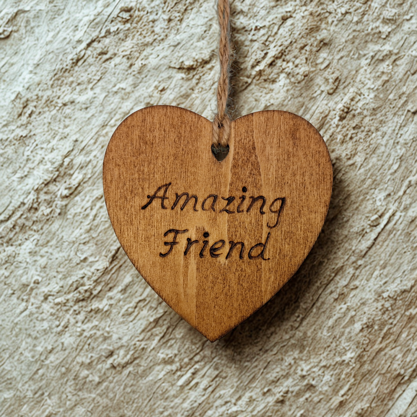 Heart-shaped wooden ornament, hand-drawn with pyrography, featuring the engraved phrase "Amazing Friend" in a decorative script, set against a light, plain background.