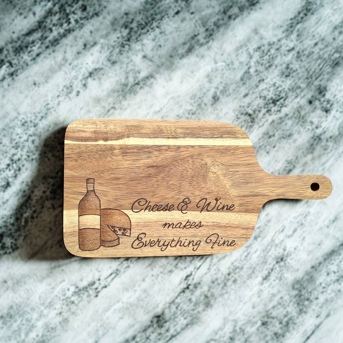 Wooden chopping board with "Cheese & Wine makes everything fine" with a drawing of a wine bottle and a wheel of cheese hand burnt into the wood
