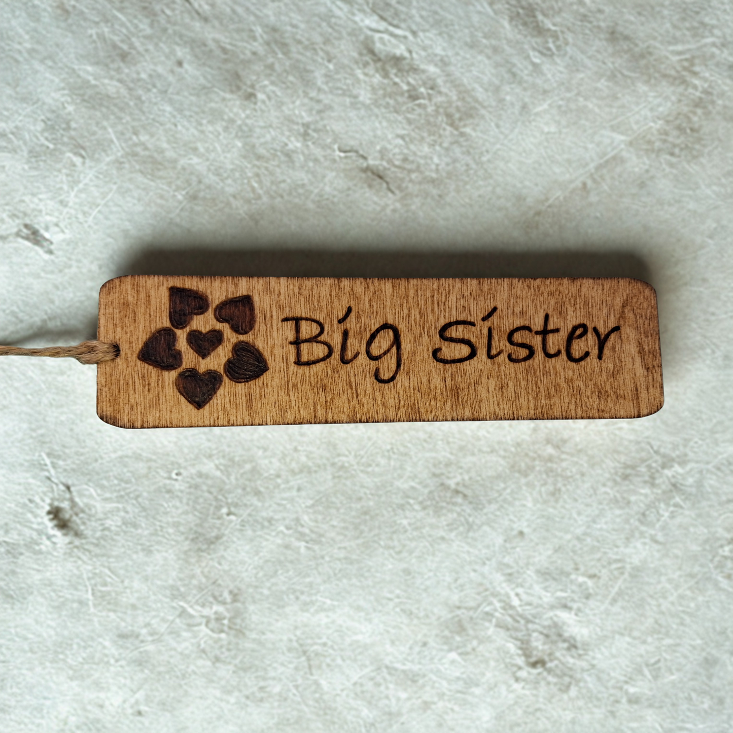 Dark wood bookmark with "Big Sister" pyrography and a flower head made from hearts illustration.
