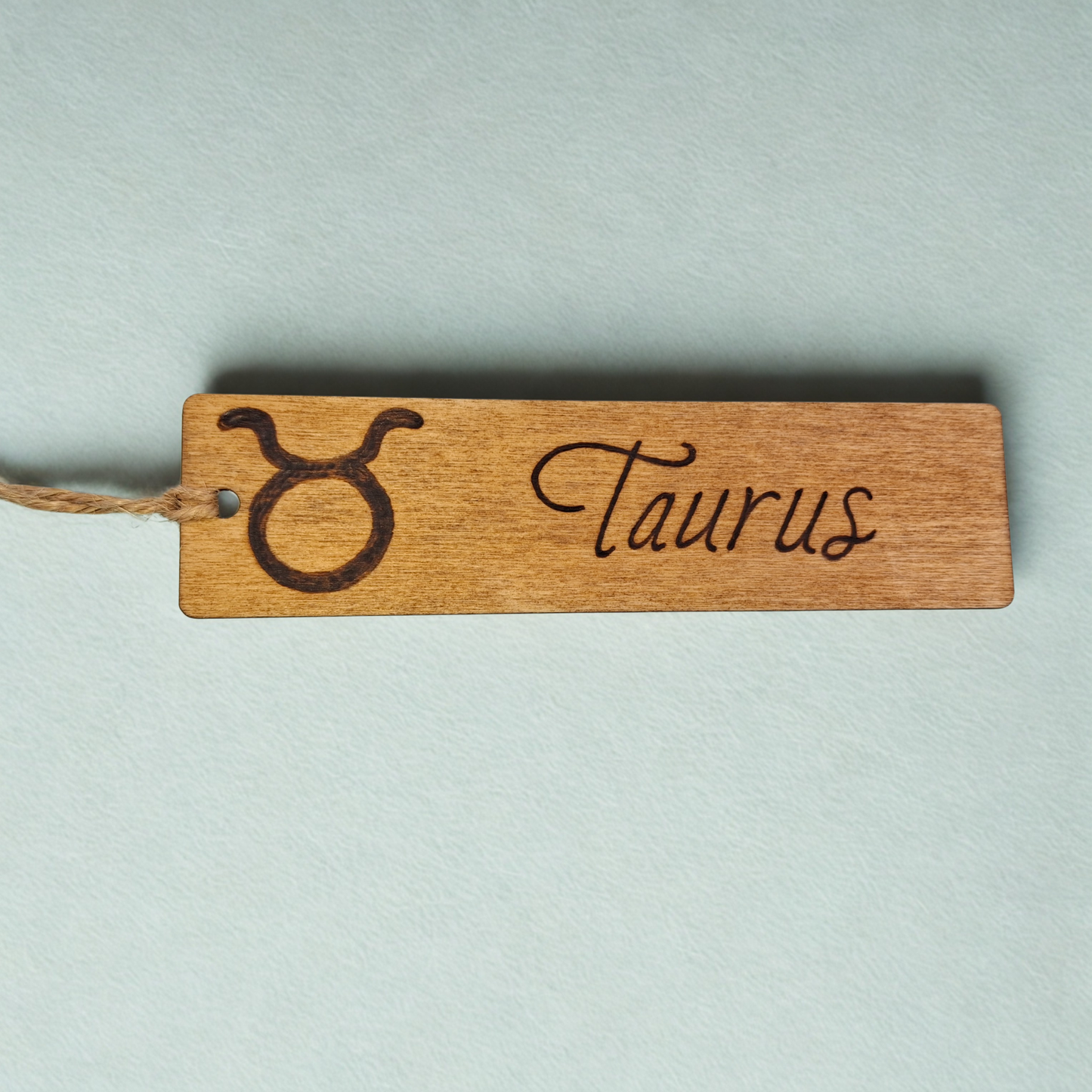 Dark wood bookmark with "Taurus" pyrography and a star sign illustration.