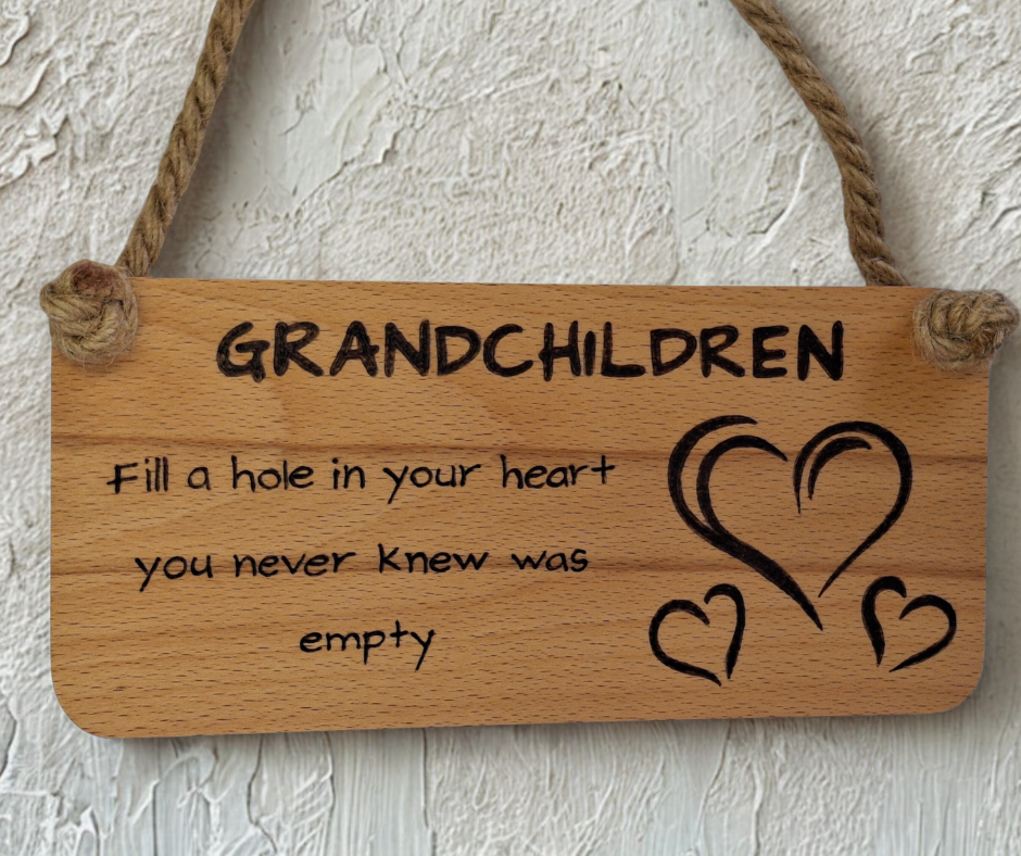 Wooden plaque hand-burnt with "Grandchildren fill a hole in your heart you never knew was empty" pyrography and three heart illustrations, hung by a thick jute rope.