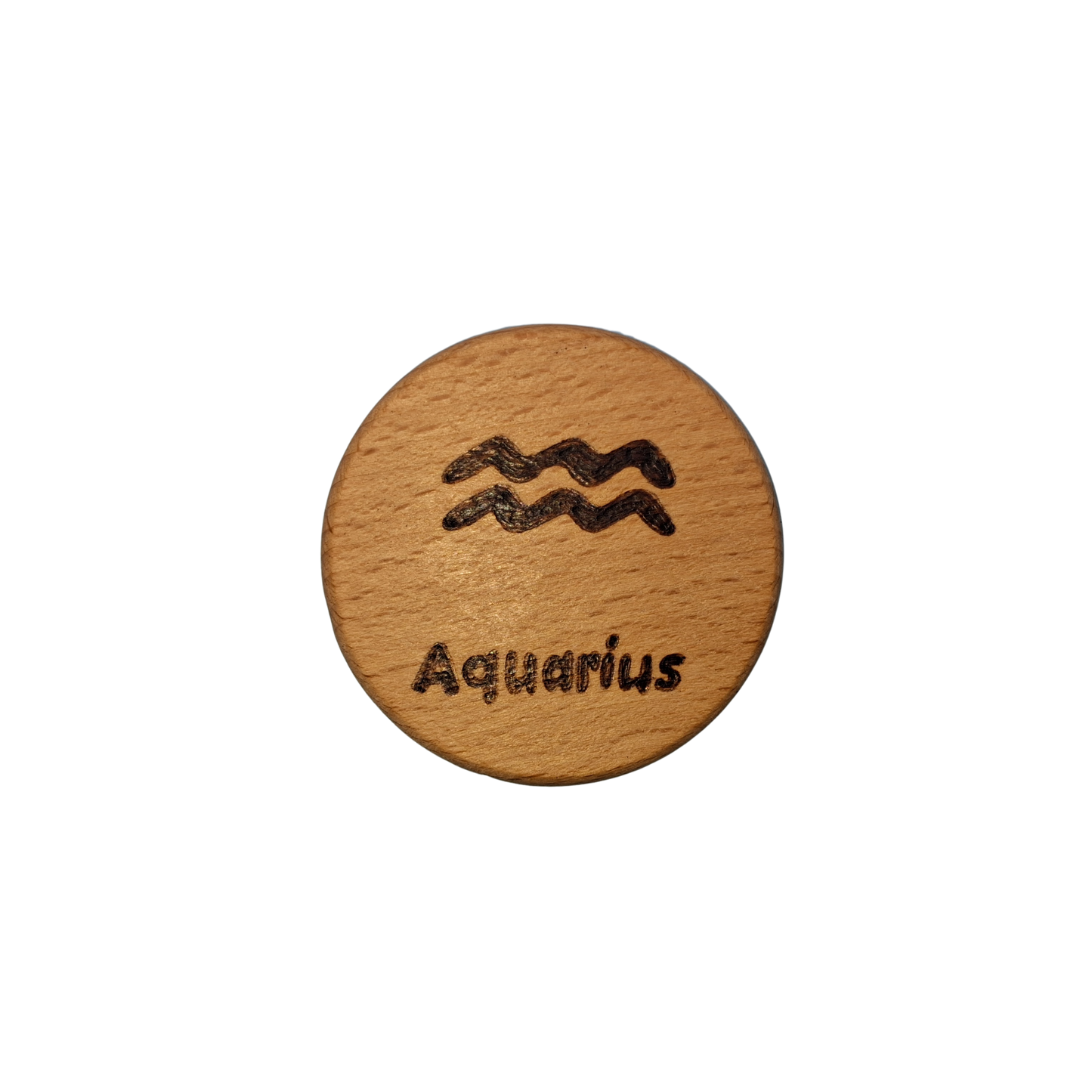 Close-up of a light-colored beechwood circle, 5cm in diameter and 0.4cm thick, featuring the words "Aquarius" and an illustration of the star sign symbol, hand-burned into its surface using pyrography. The wood has a smooth, waxed finish and the text is clearly legible.