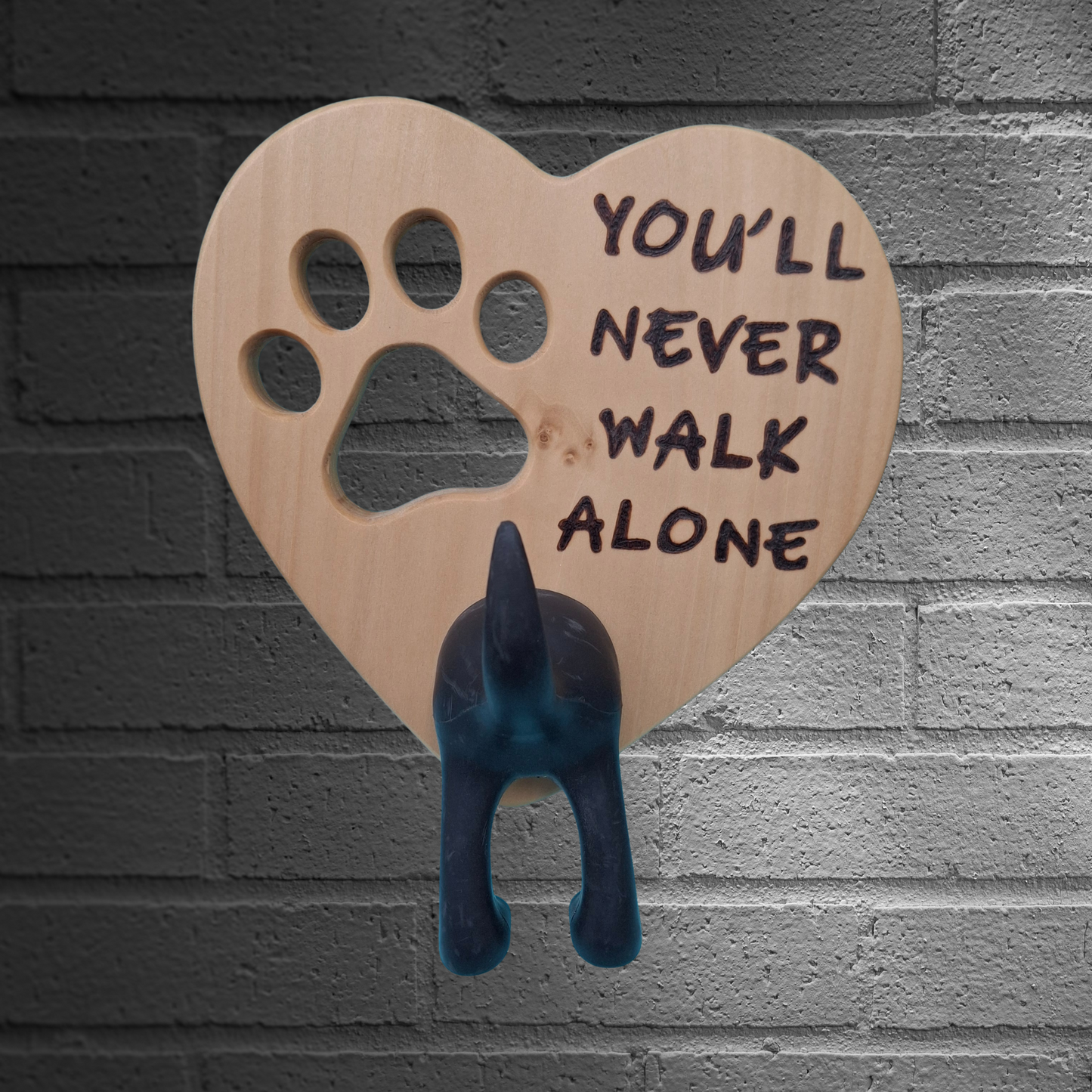 Heart-shaped wooden dog lead hanger with paw print cutout and 'You'll Never Walk Alone' text, featuring a black dog silhouette hook