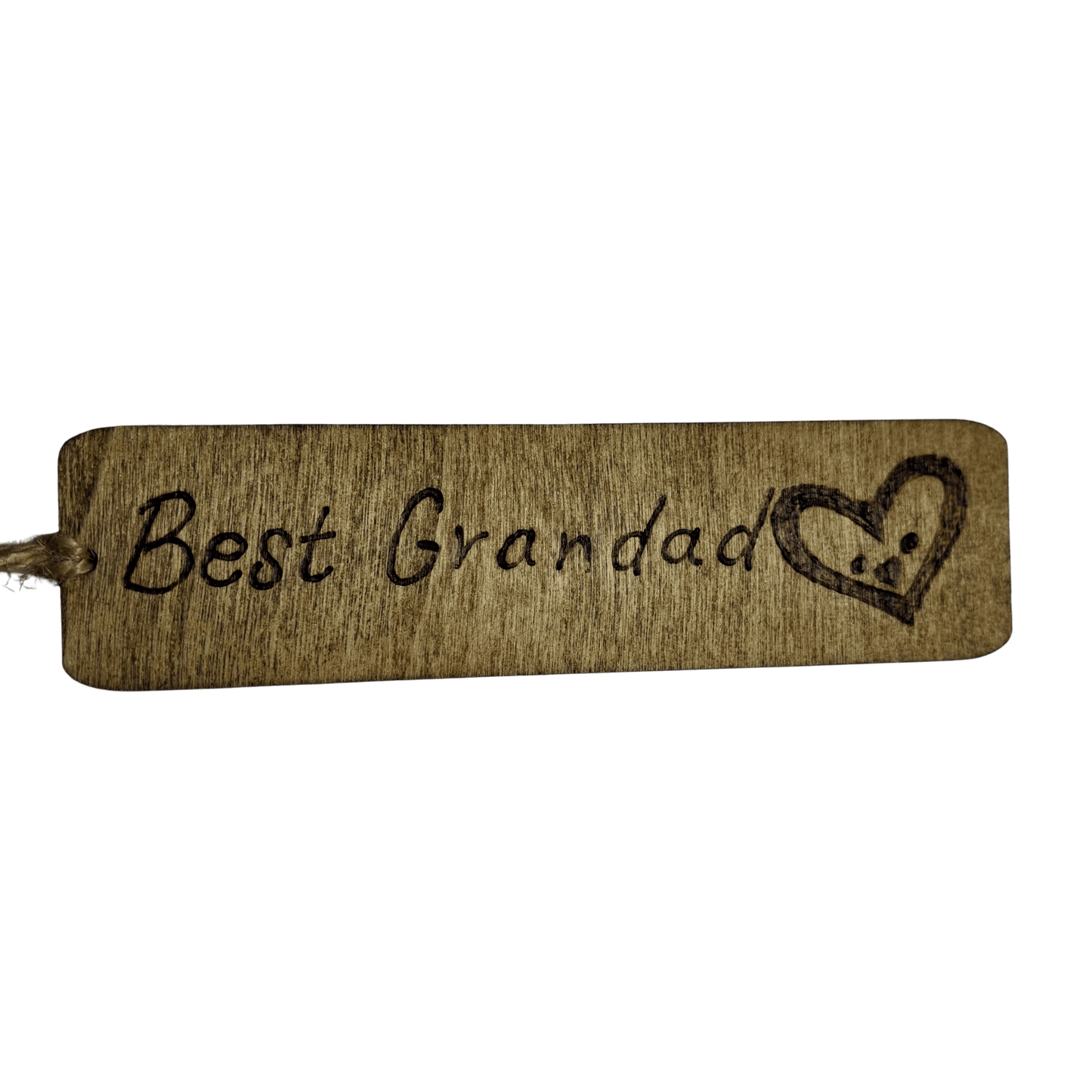 A close-up of a wooden bookmarj The bookmark has rounded corners and a jute string tied through a hole on the left side. The surface is decorated with a pyrography design featuring the text "Best Grandad" and a heart with two dots and a line, resembling a face.