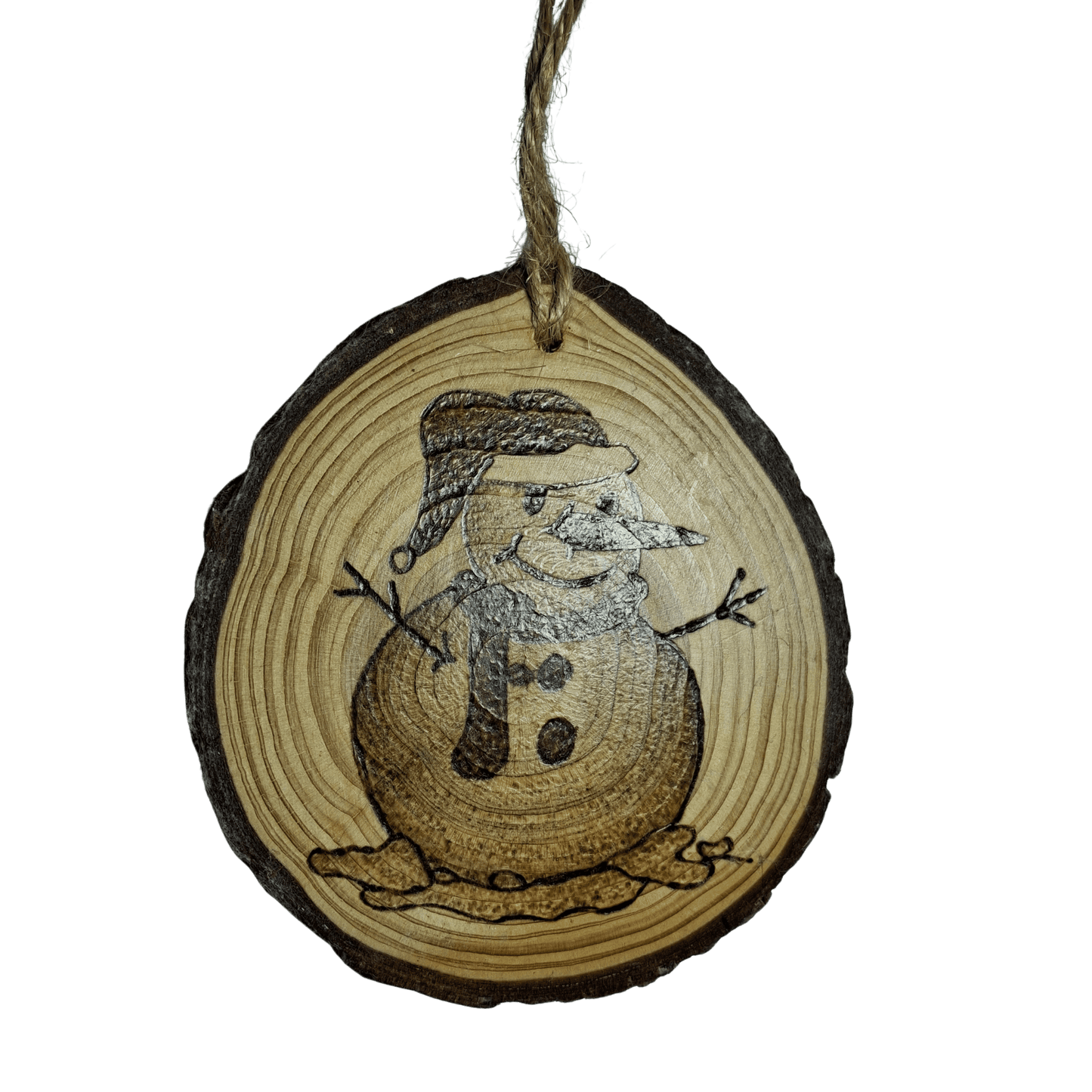 A Christmas ornament on a black background. The ornament is a round wooden log slice with a jute rope for hanging. It is decorated with a pyrography design of a snowman with a hat and scarf, with snow melting around his base.