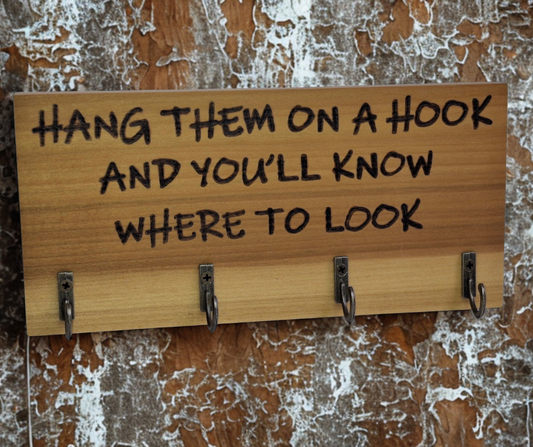 A four-key hook hanger crafted from two-tone Tulipwood, featuring hand-burnt lettering that reads "Hang them on a hook so you know where to look." The wood has visible grain, showcasing its natural variations.