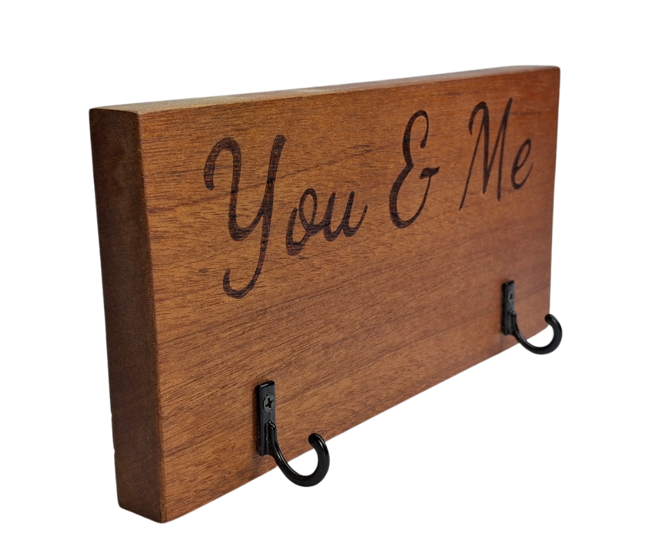 A dark sapele wood 2-hook key hanger with hand-decorated pyrography wording "You & Me".