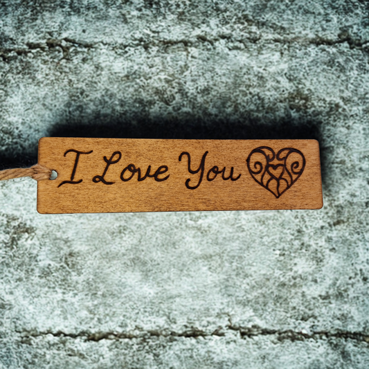 Dark wood bookmark with "I love you" pyrography and a patterned heart illustration.