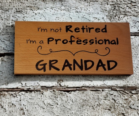 Wooden plaque hand-decorated with "I'm not retired I'm a professional Grandad" pyrography.