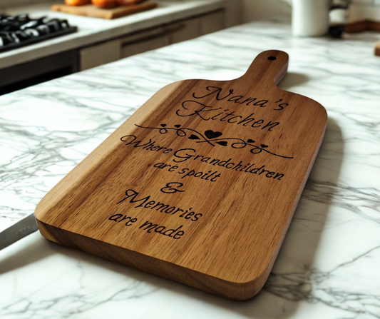 A multicolored, hand-decorated pyrography chopping board with the words "Nana's Kitchen where grandchildren are spoilt and memories are more" and a decorative heart divider.