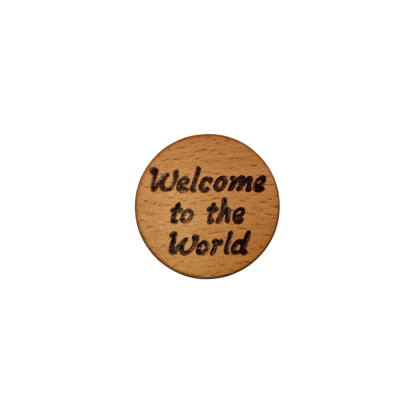 Close-up of a light-colored beechwood circle, 5cm in diameter and 0.4cm thick, featuring the words "Welcome to the world" hand-burned into its surface using pyrography. The wood has a smooth, waxed finish and the text is clearly legible.