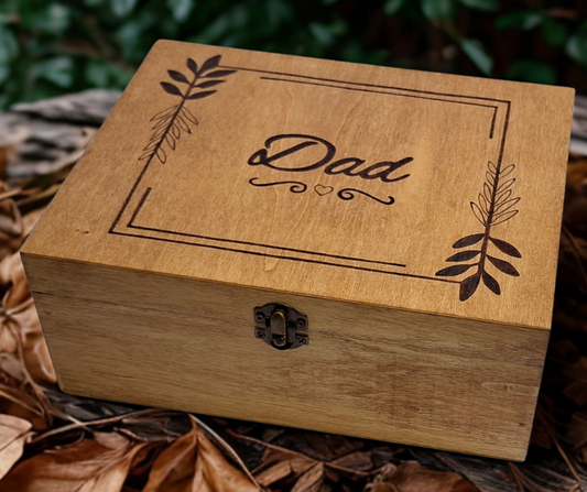 Decorative wooden box with "Dad" burnt in a framed square, accented by delicate leaf accents and a heart below.