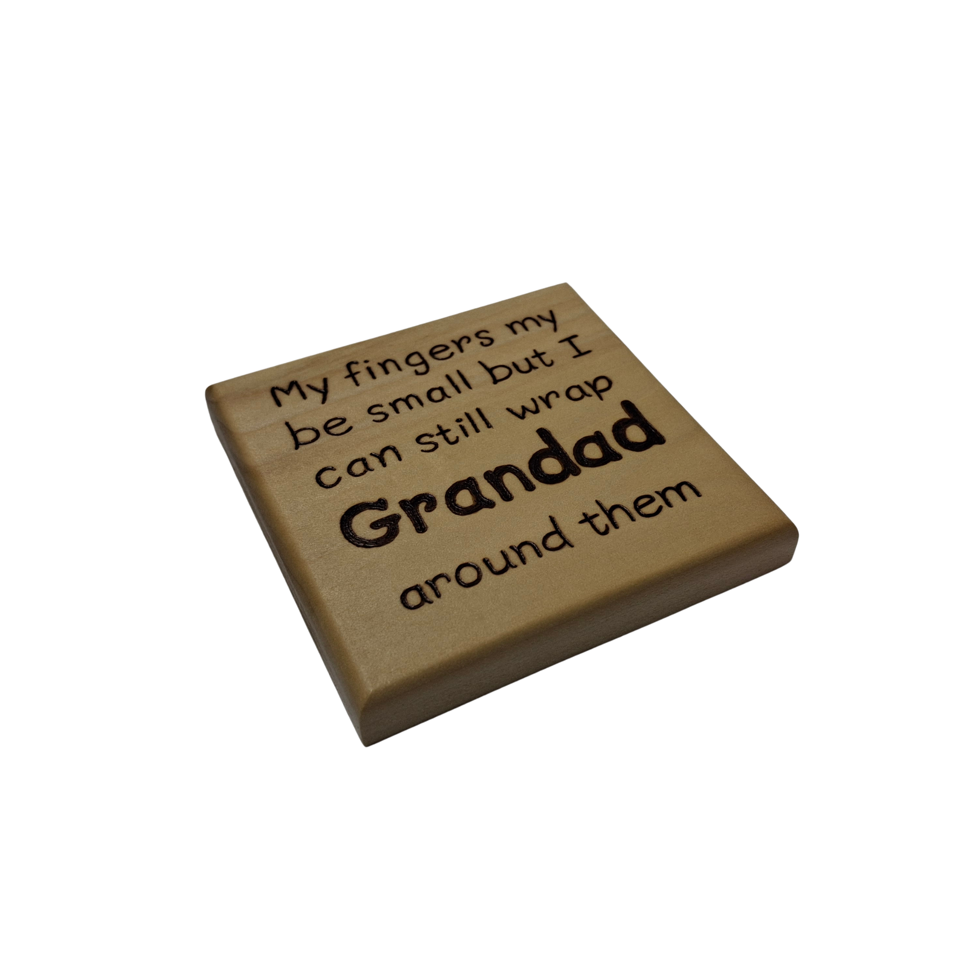 A light wood coaster, square in shape, with pyrography lettering. The text reads: "My fingers my be small but I can still wrap Grandad around them". The word "Grandad" is significantly larger and bolder than the rest of the text.