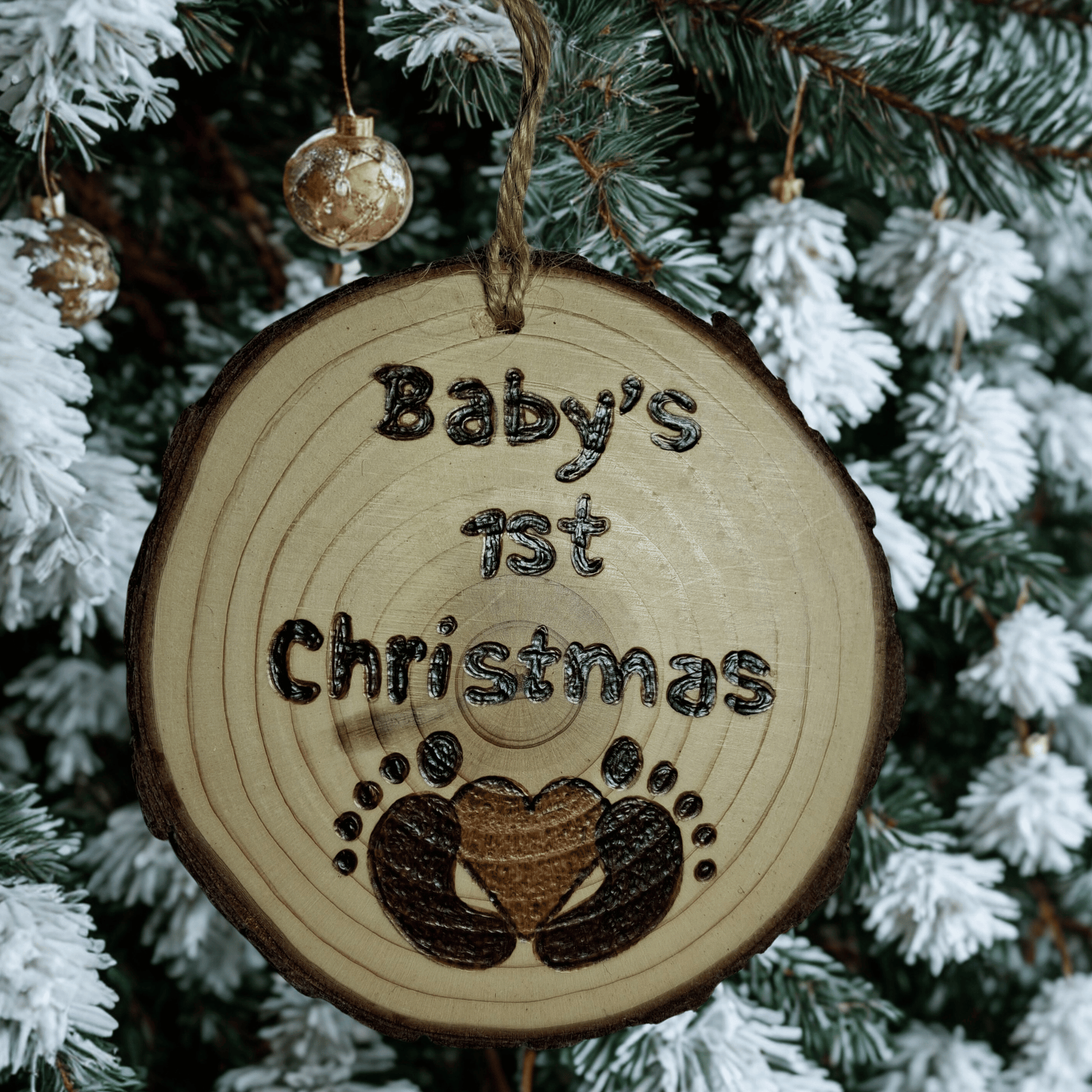 Wooden ornament with 'Baby's 1st Christmas' text and footprints on a Christmas tree background.