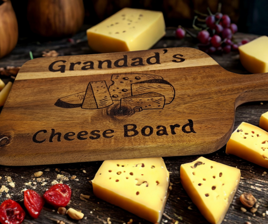 A multicolored, hand-decorated pyrography chopping board with the words "Grandad's Cheese Board" and illustrations of cheese chunks.