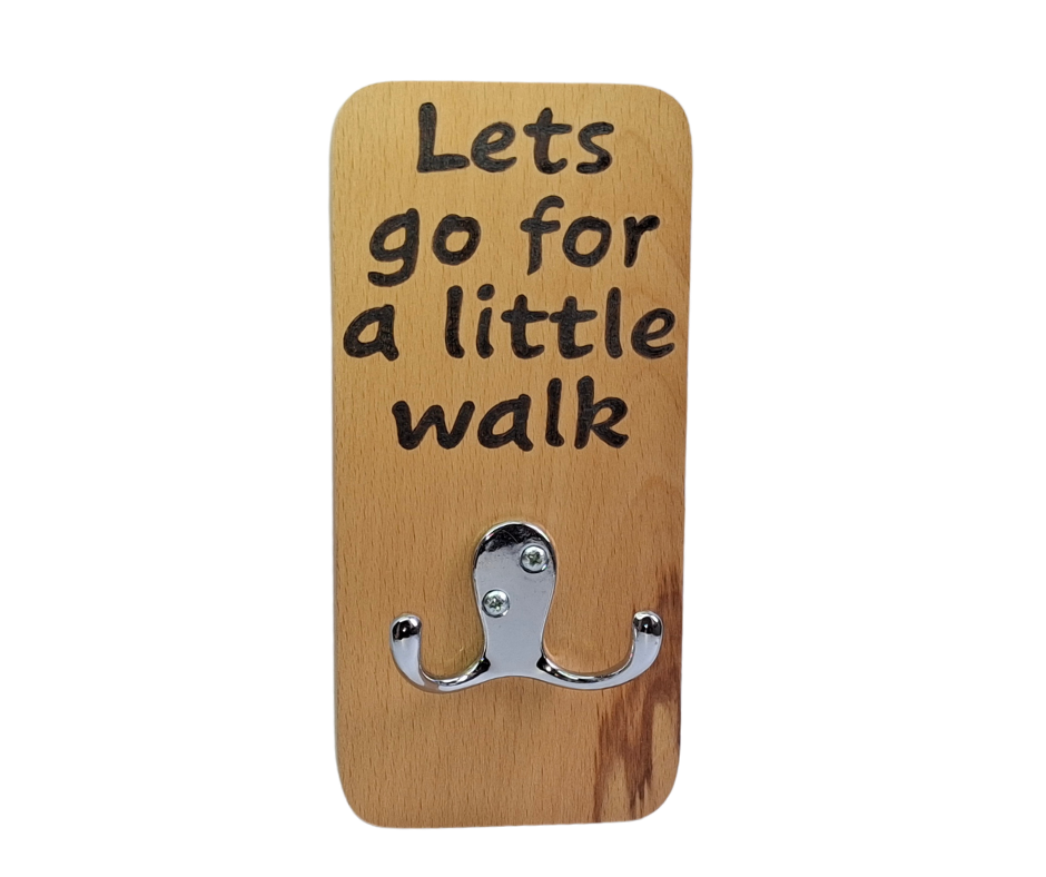 A hand-cut beechwood lead hanger with a double chrome hook for hanging leads. It's decorated with pyrography wording "Let's go for a little walk" and finished with hardwax oil.