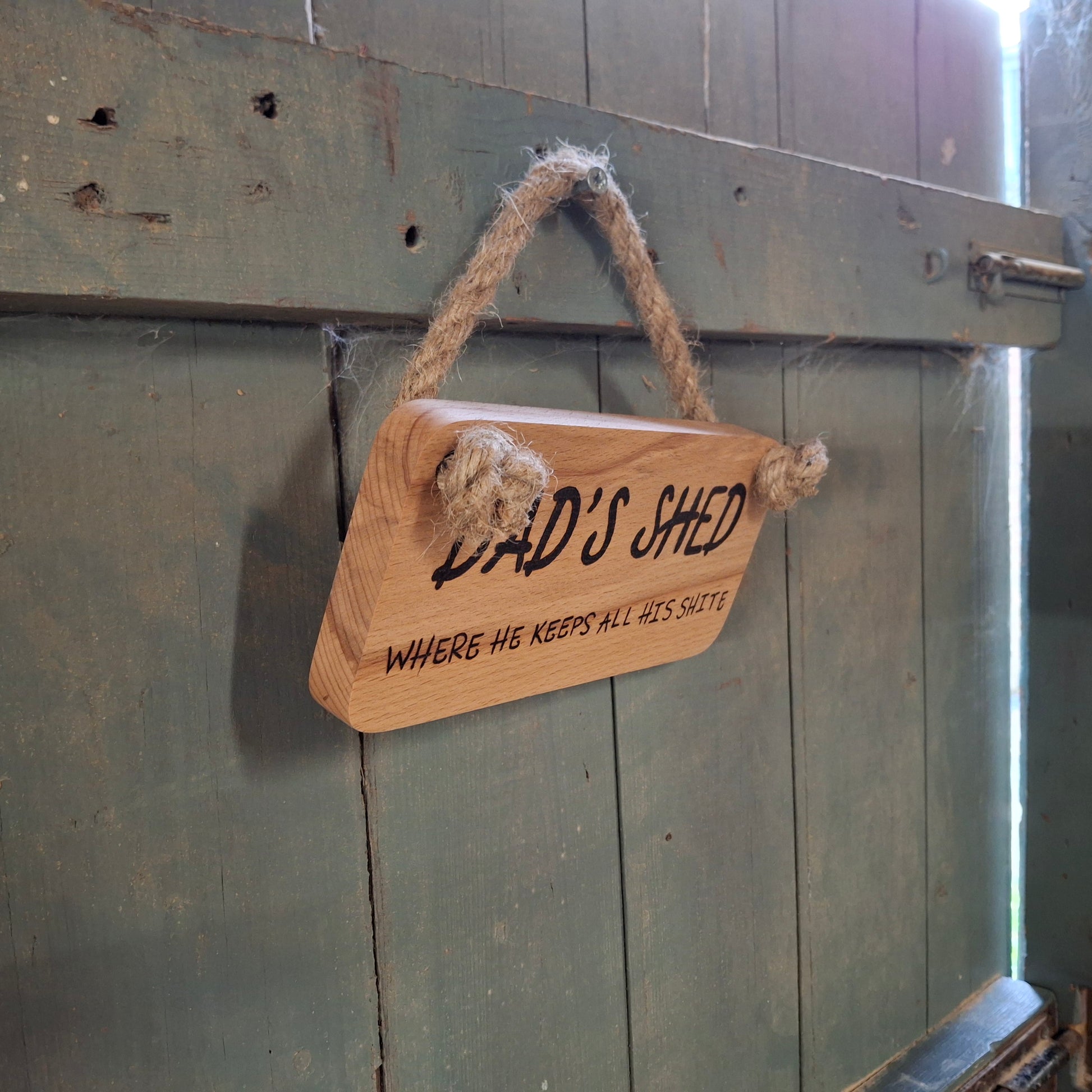 Wooden sign with 'Dad's Shed' text hanging on a wooden door.