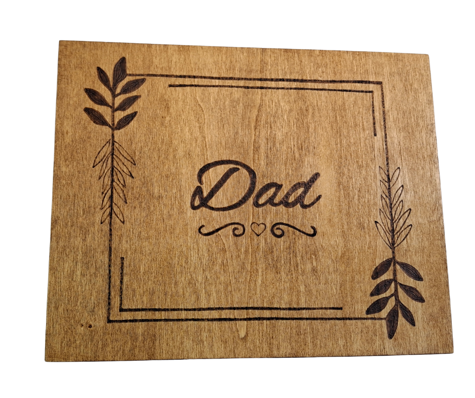 Decorative wooden box with "Dad" burnt in a framed square, accented by delicate leaf accents and a heart below.