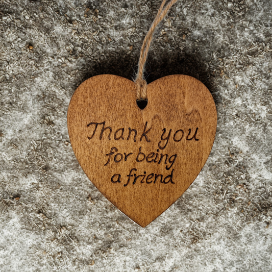 
Heart-shaped wooden ornament, hand-drawn with pyrography, featuring the engraved phrase "Thank you for being a friend" in a decorative script, set against a light, plain background.