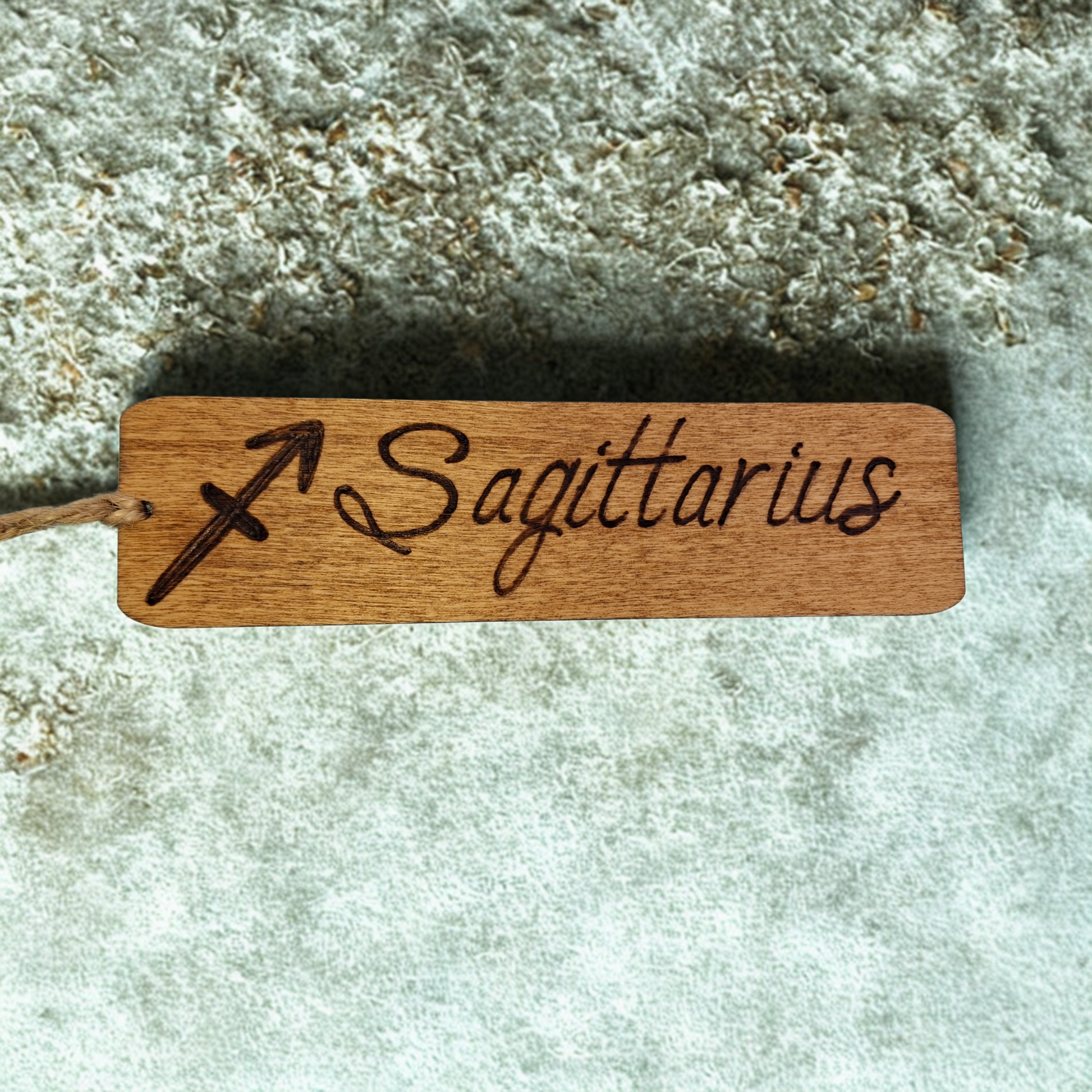 Dark wood bookmark with "Sagittarius" pyrography and a star sign illustration.