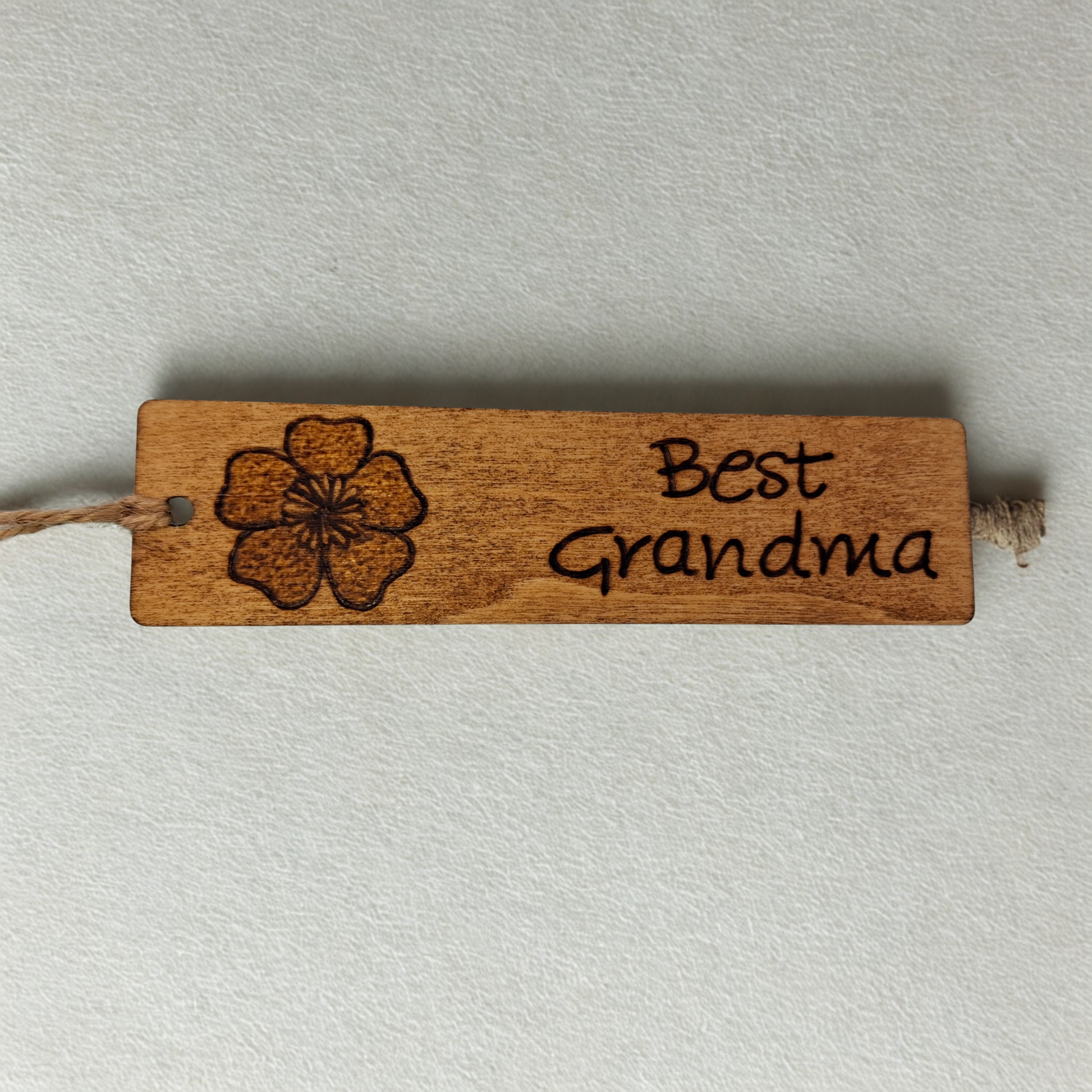Dark wood bookmark with "Best Grandma" pyrography and a flower head illustration.