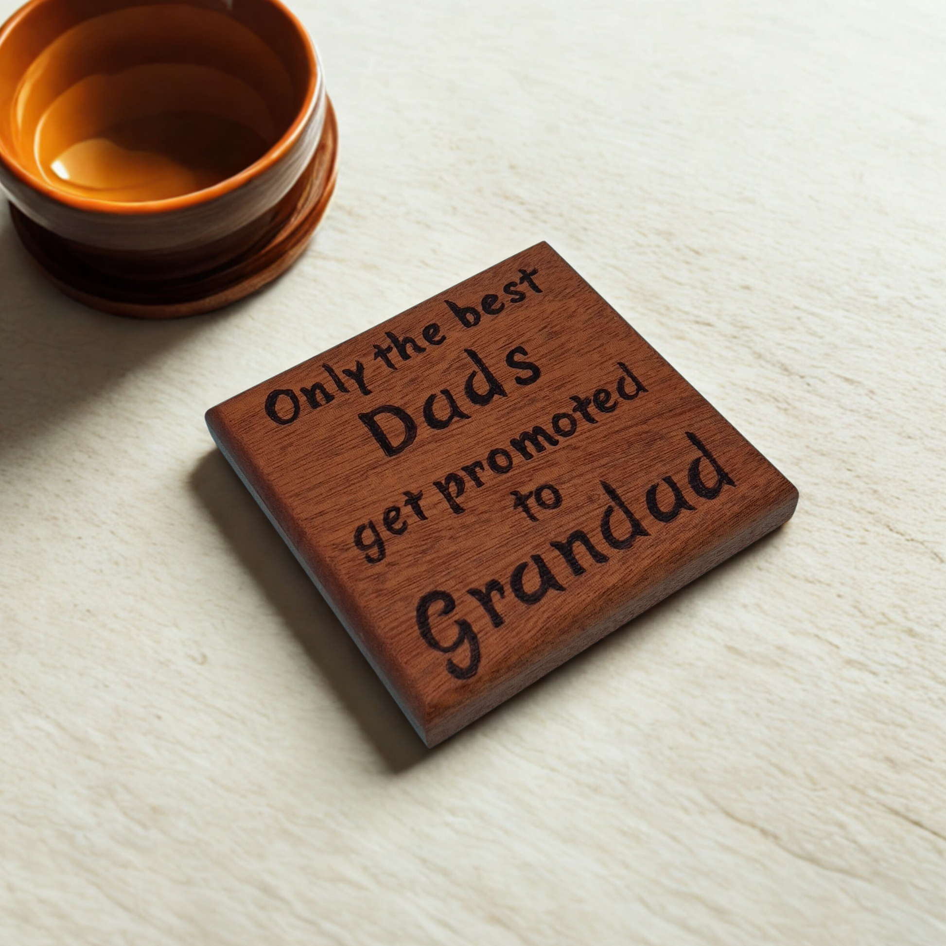 Dark wooden coaster with pyrography text reading 'Only the best Dads get promoted to Grandad'