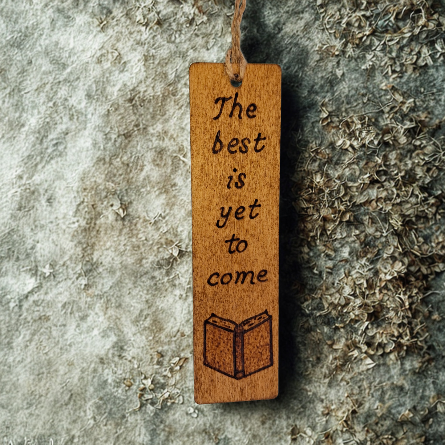 Dark wood bookmark with "The best is yet to come" pyrography and a open book illustration.