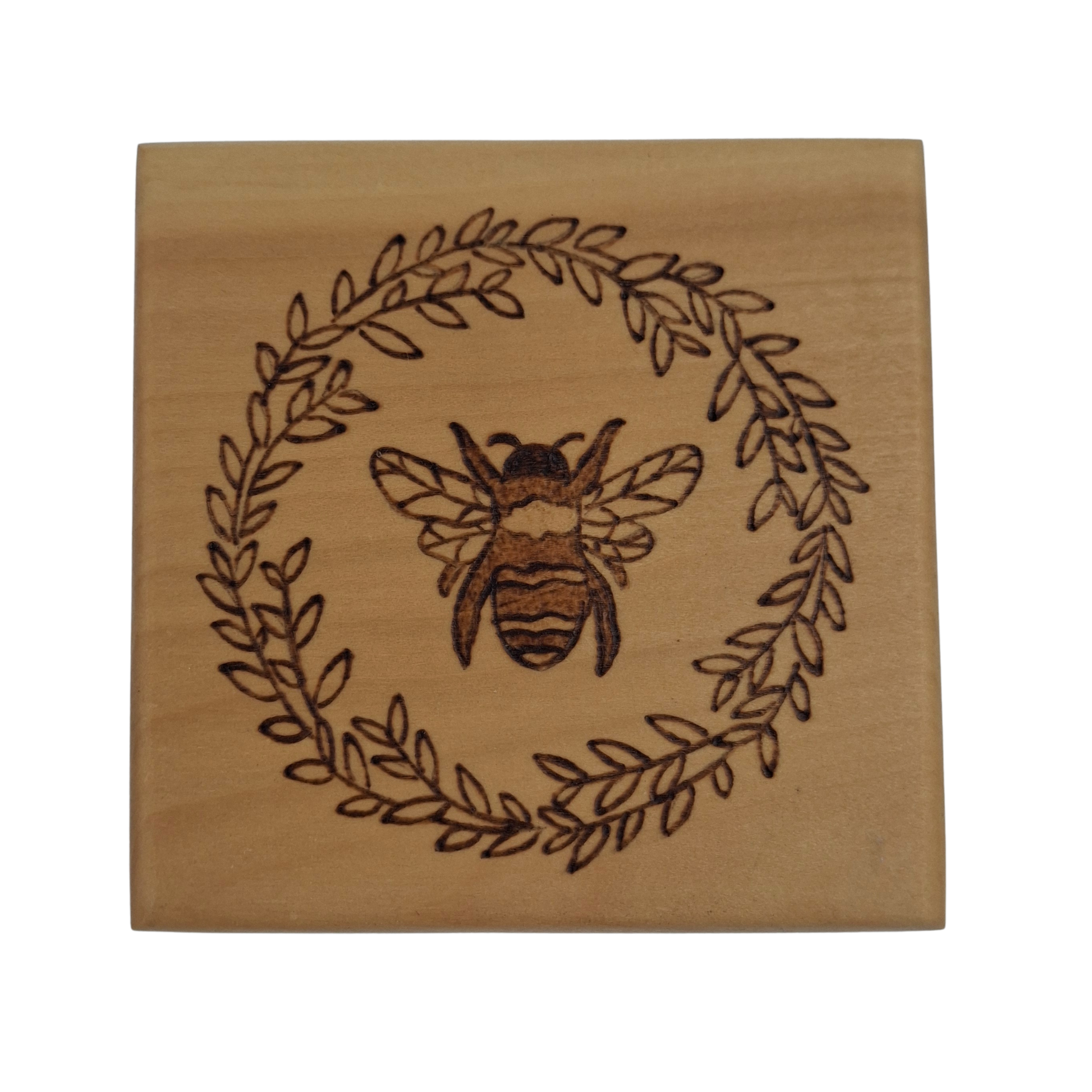 Wooden coaster with hand burnt bee and leaf design on a white background